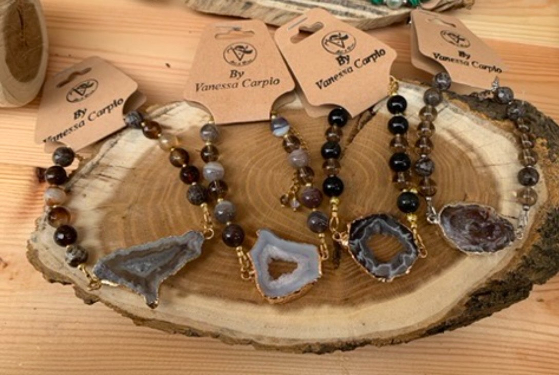 Biżuteria handmade z naturalnych kamieni – bransoletki z agatem na drewnianym tle.